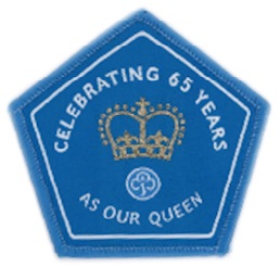 Pentagon-shaped badge in blue with blue binding. Text: Celebrating 65 Years as our Queen.