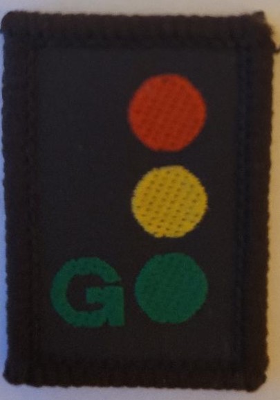 Brown rectangular badge with coloured dots laid out like traffic lights.