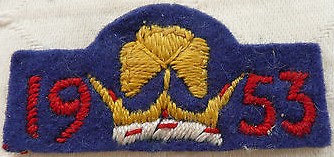 Blue felt badge featuring a crown topped with a trefoil in gold, and the text: 1953