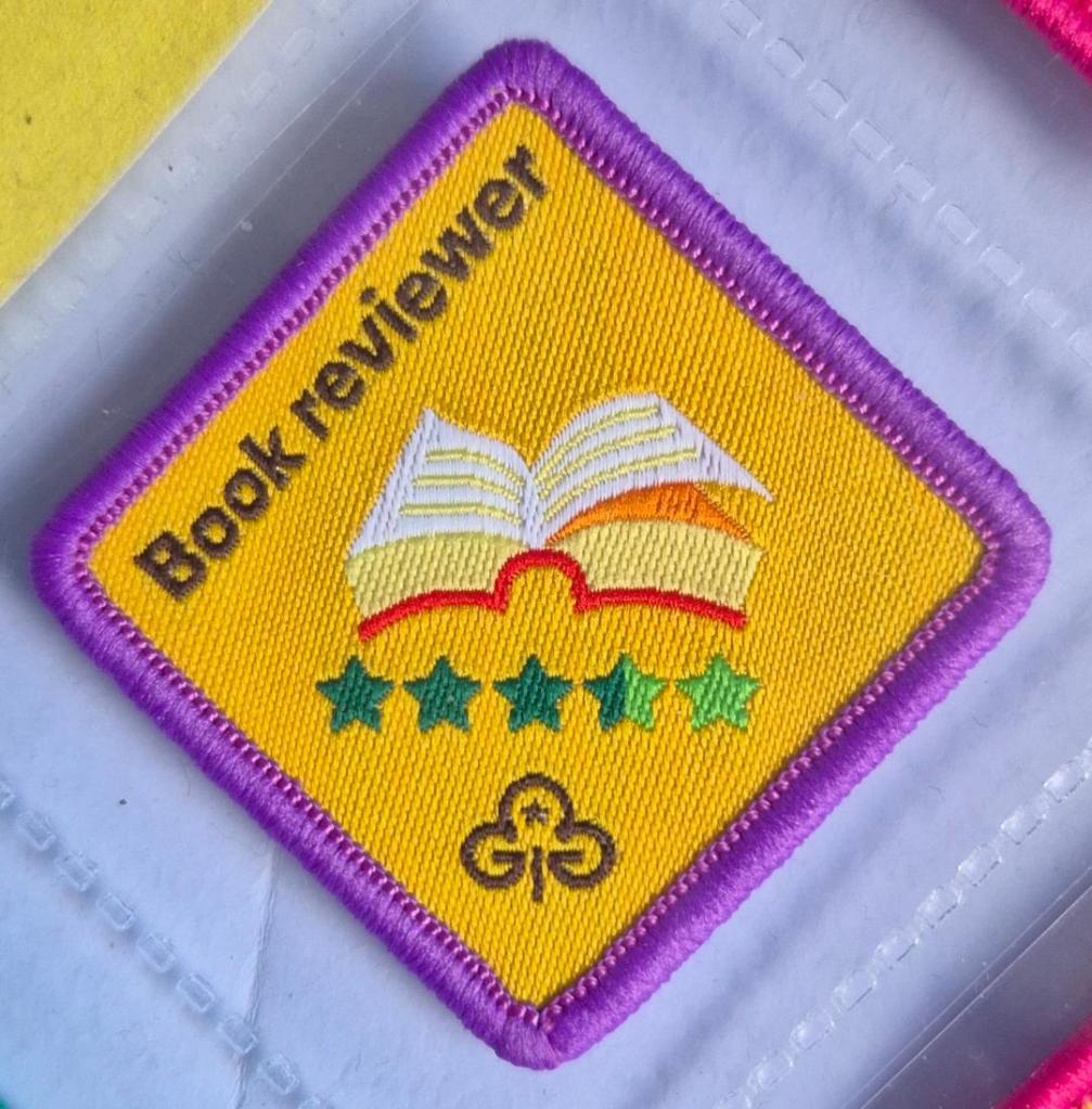 Brownie Book Reviewer badge, purple binding, open book logo
