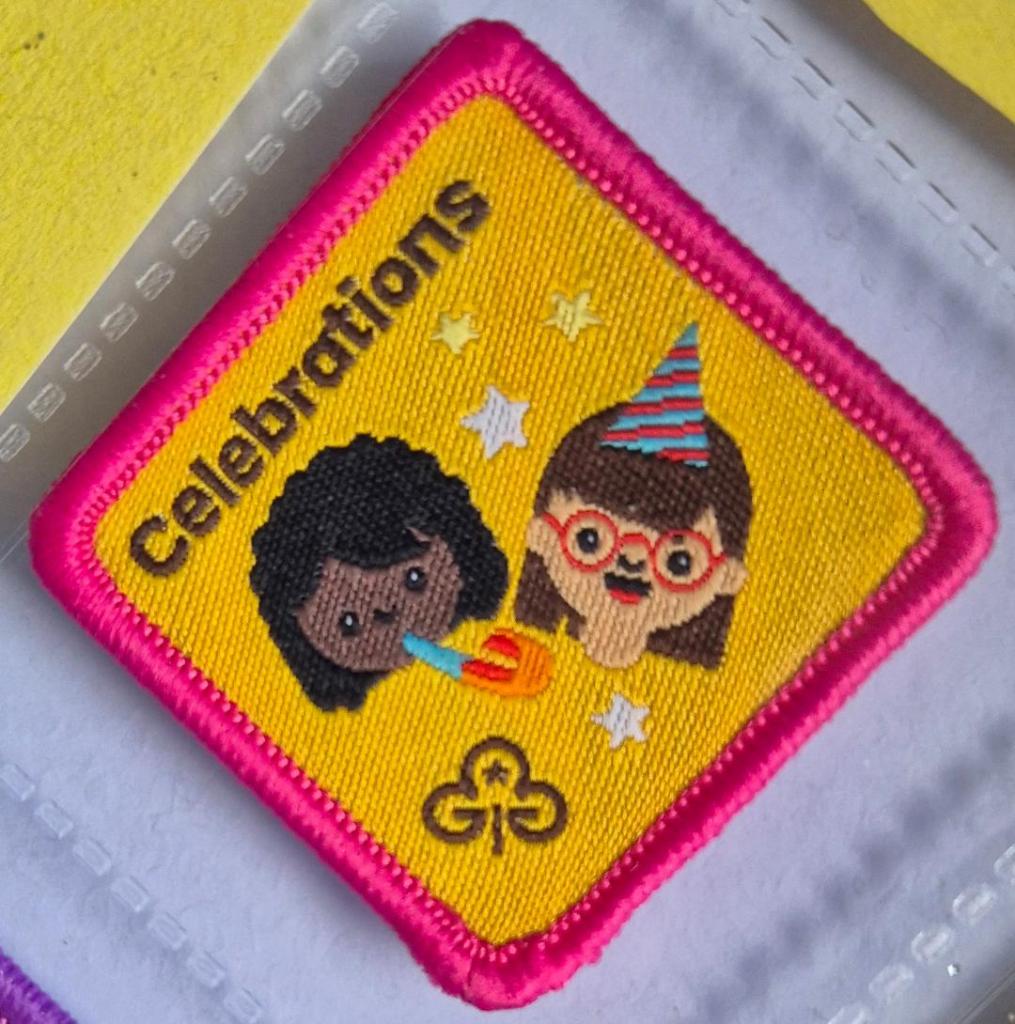 Brownie Celebrations badge, dark pink binding, logo of two girls with party accessories