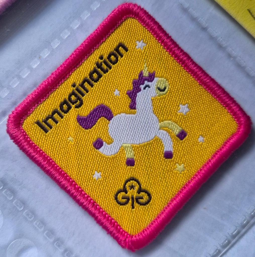 Brownie Imagination badge, dark pink binding. Unicorn logo.