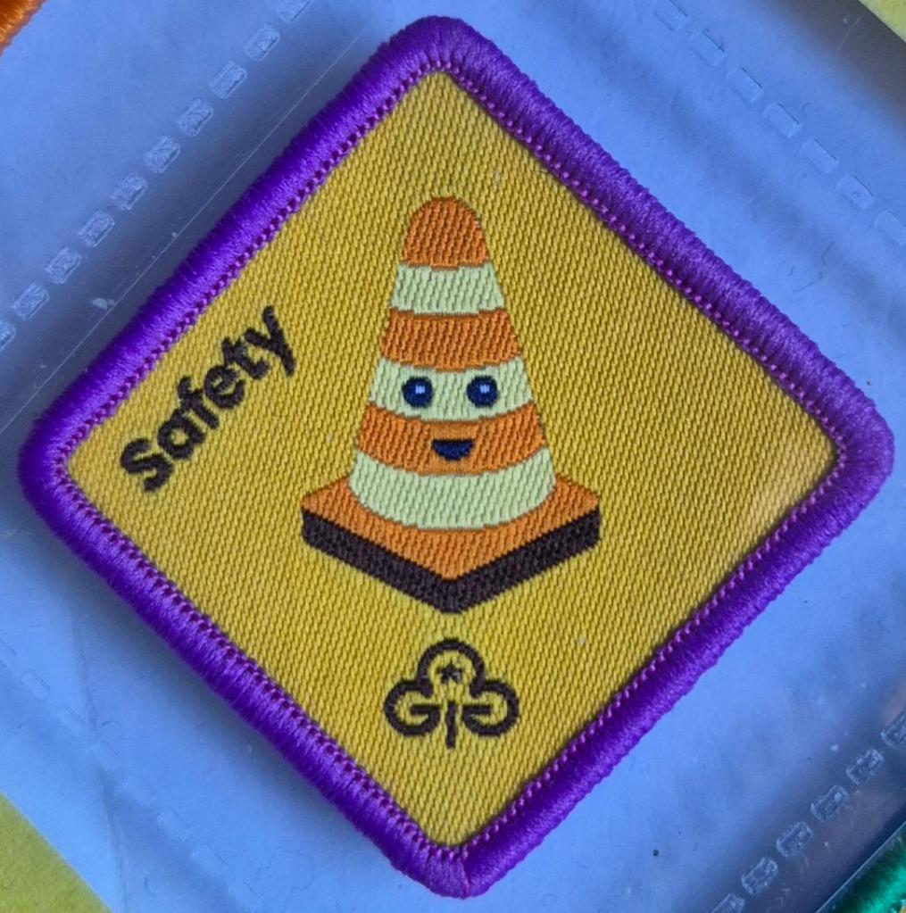 Brownie Safety badge, purple binding. Traffic cone logo.