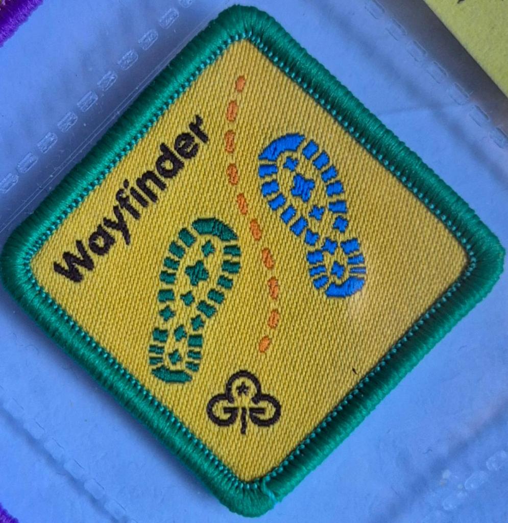 Brownie Wayfinder badge, green binding. Walking-boot bootprints logo.