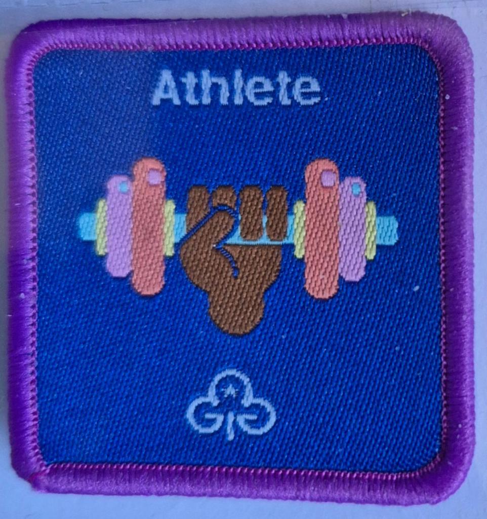 Guide Athlete badge, purple binding.  Hand lifting dumbbell logo