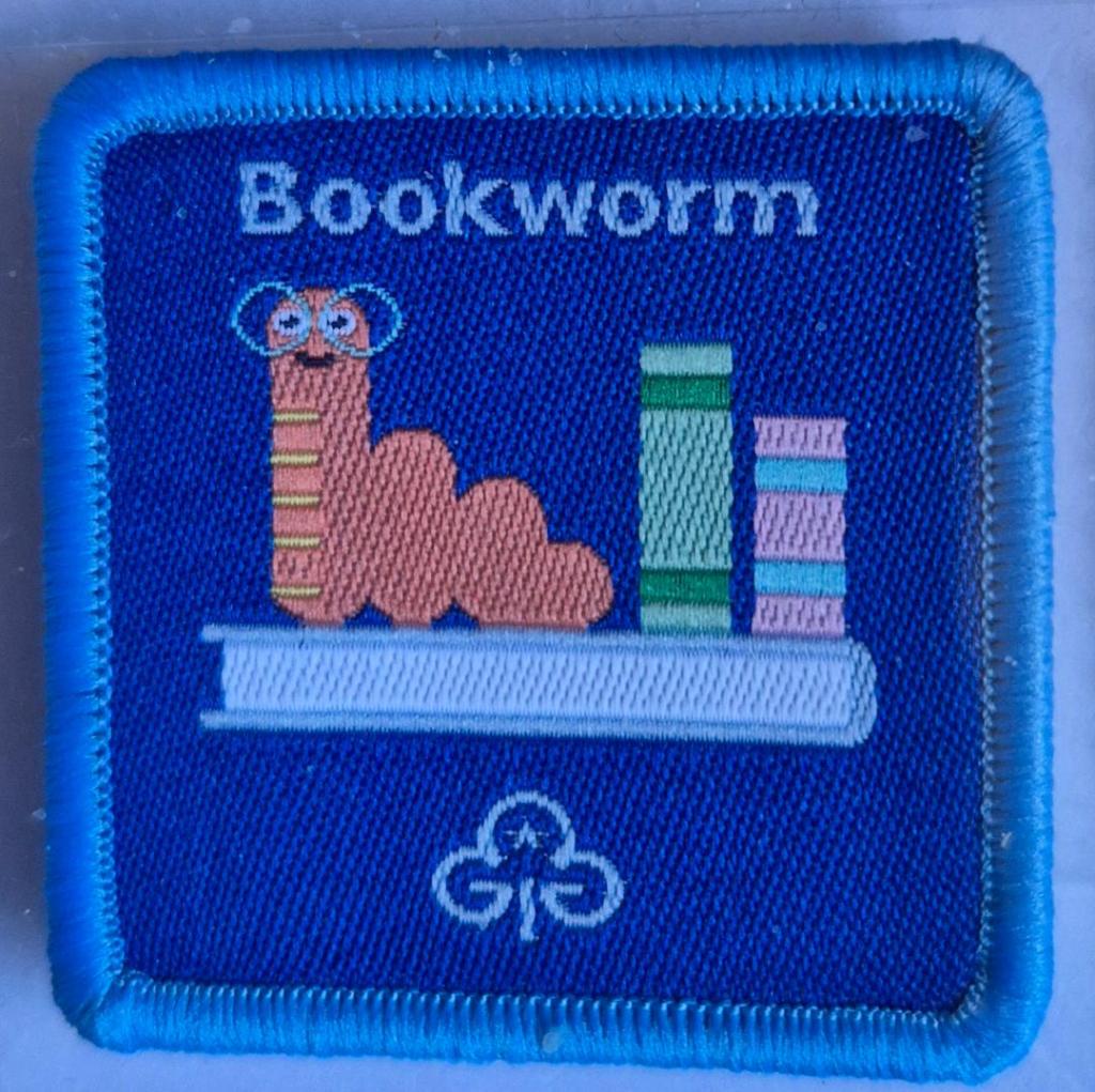 Guide Bookworm badge, blue binding.  Bookworm on bookshelf logo