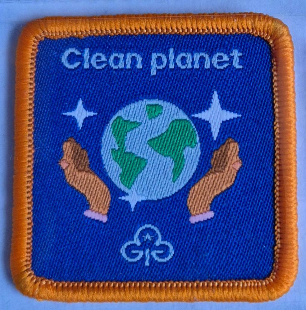 Guide Clean Planet badge, orange binding.  Hands around globe logo.