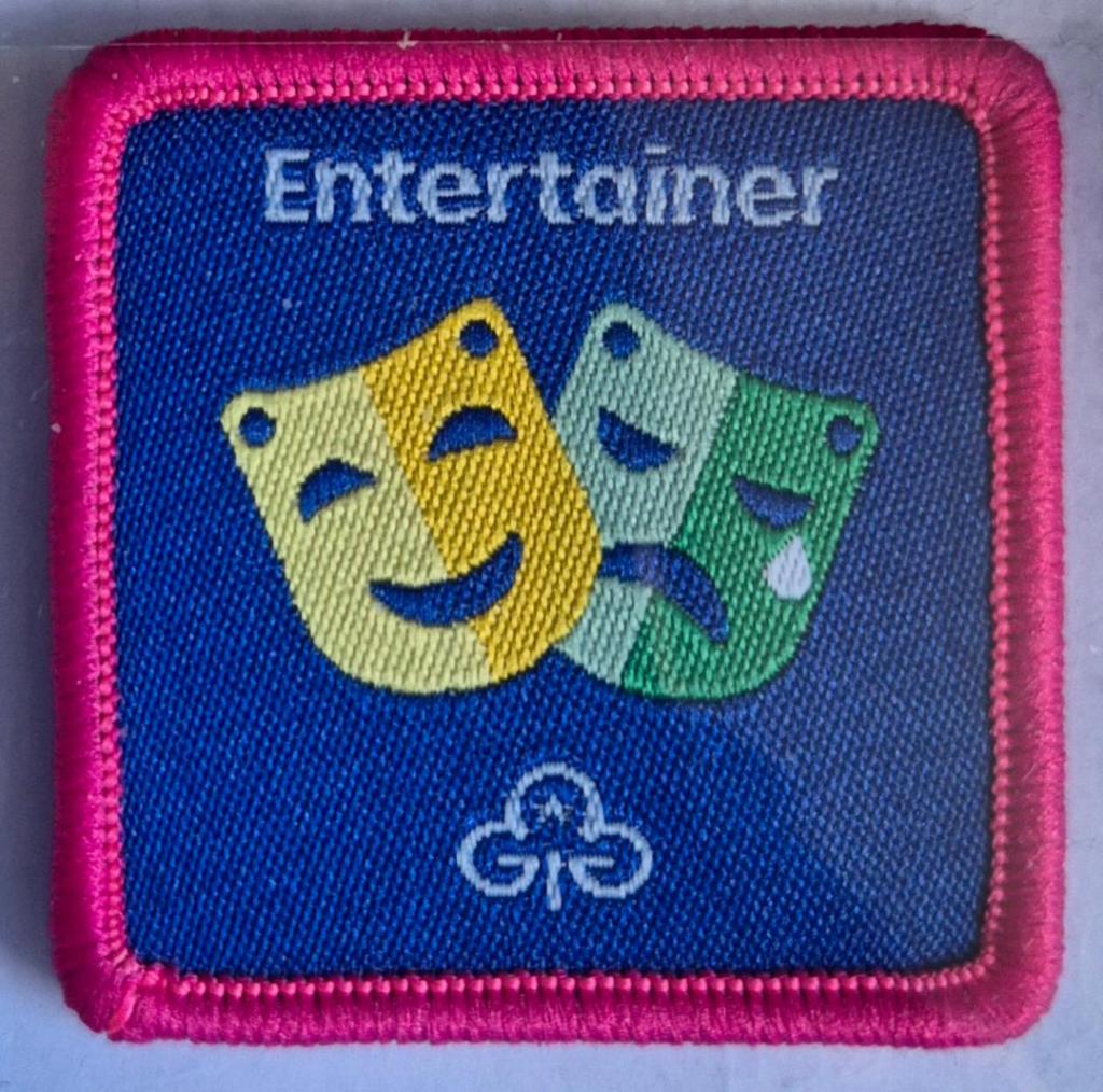 Guide Entertainer badge, dark pink.  Twin masks logo.