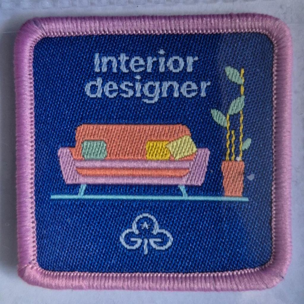 Guide Interior Designer badge, light pink binding.  Sofa and plants logo.