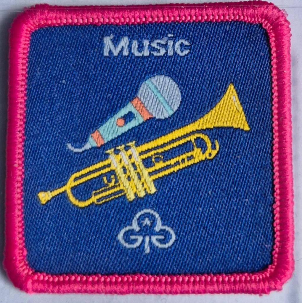 Guide Music badge, dark pink binding.  Trumpet and microphone logo.