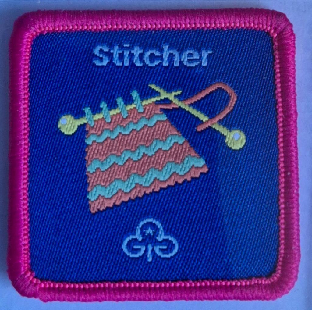 Guide Stitcher badge, dark pink binding.  Striped knitting on needles logo.