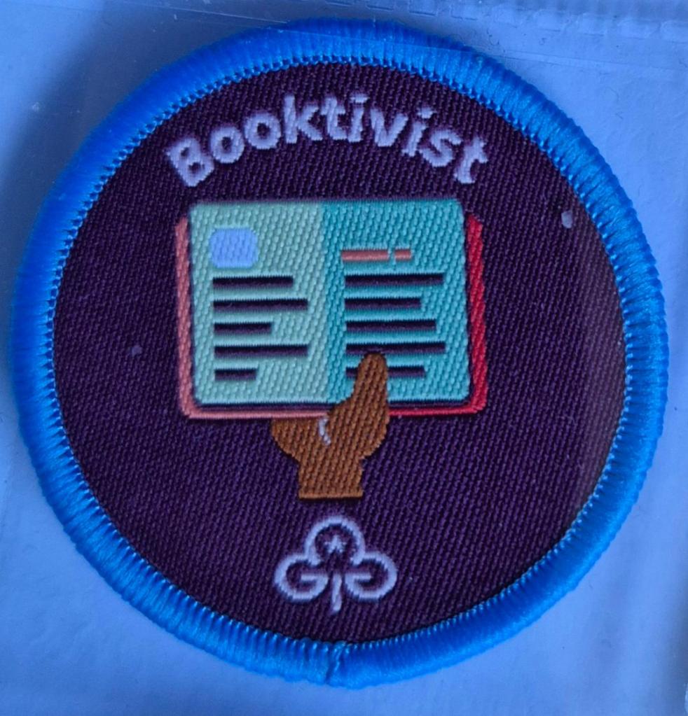 Ranger Booktivist badge, blue binding.  Open book in hand logo.