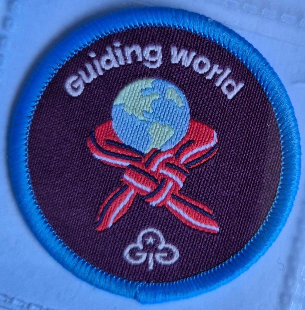 Ranger Guiding World badge, blue binding.  Friendship-knotted necker round globe logo.